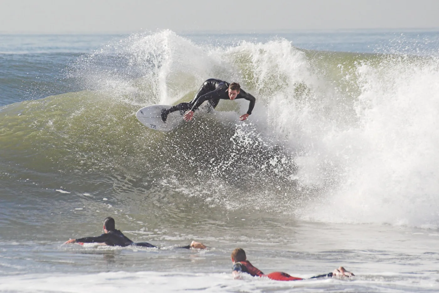 A surfer off the lip of a green wave at Cox Bay